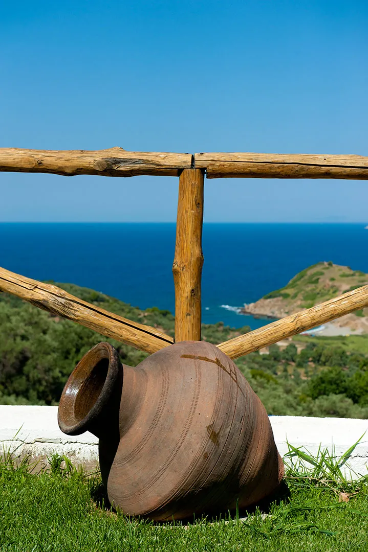 An old clay amphora on the lawn by the wooden fence