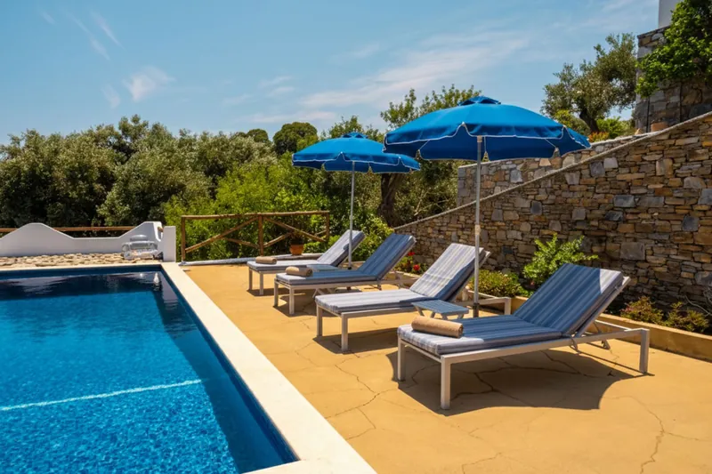 Loungers and umbrellas by the pool and the stone wall