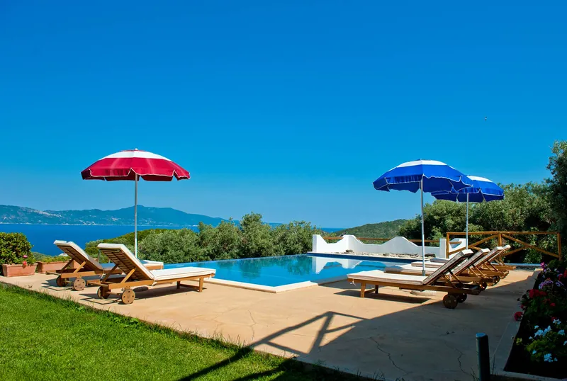 The pool, the lawn and sun umbrellas looking out to sea